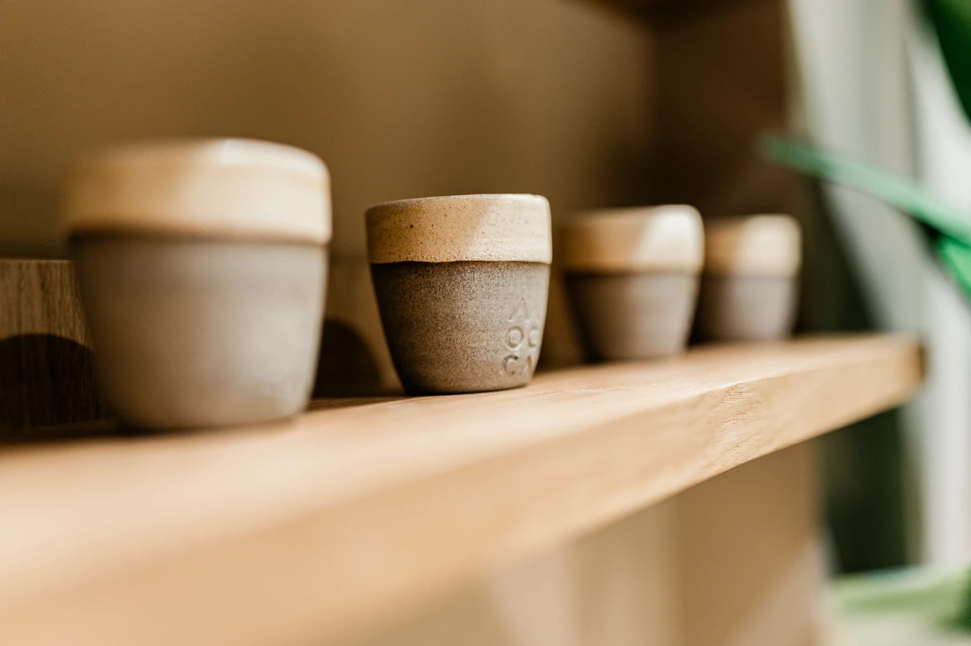 Handmade ceramic cups arranged on a wooden shelf